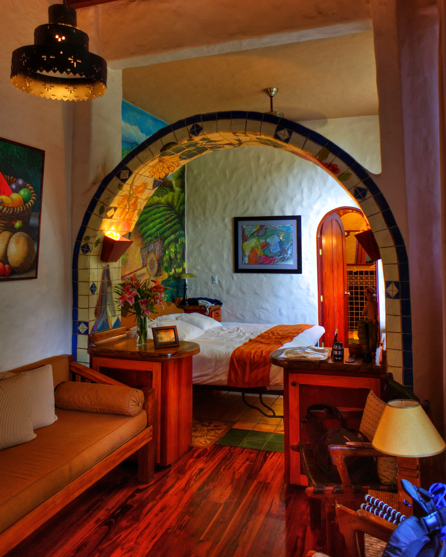 Two guests in white robes standing at an arched window overlooking lush greenery at Finca Rosa Blanca